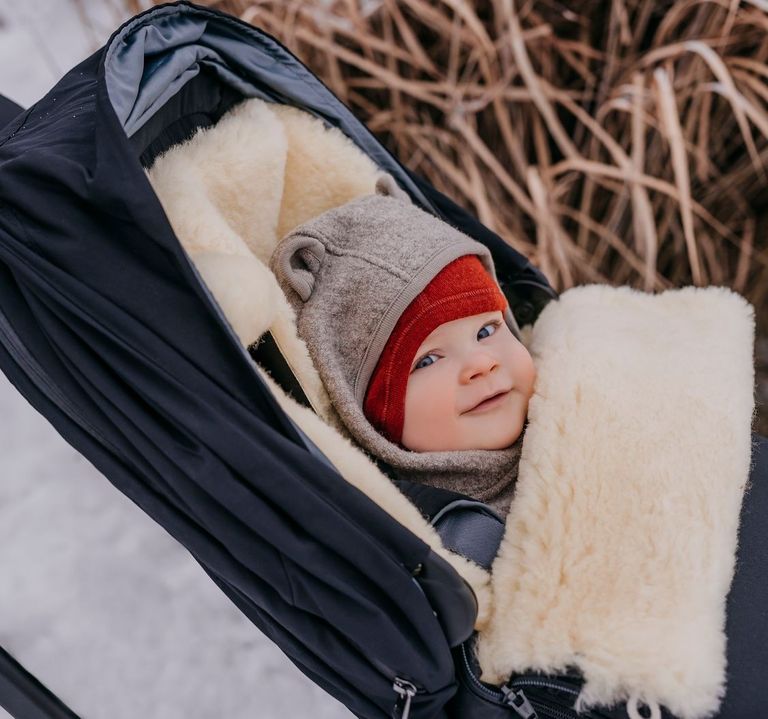 lachendes baby im winter im kaiser lammfell fußsack love the nature sand melange