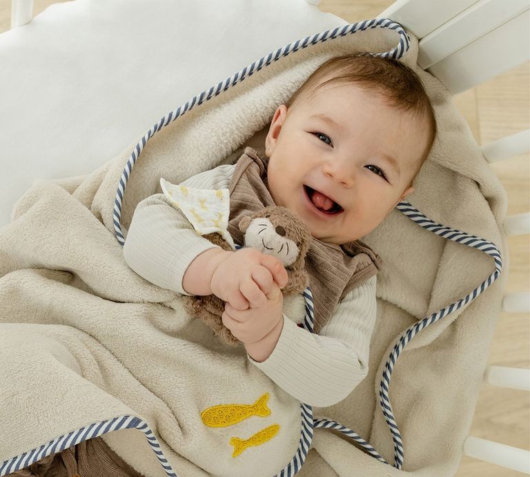 lachendes baby eingewickelt in kuschelige babydecke fehn