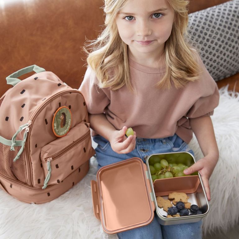 mädchen mit lässig rucksack brotzeitdose trinkflasche sitzt auf couch