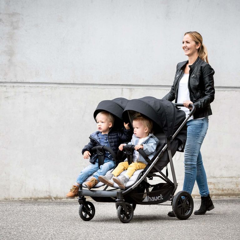 mutter schiebt zwillingskinderwagen mit zwillingen
