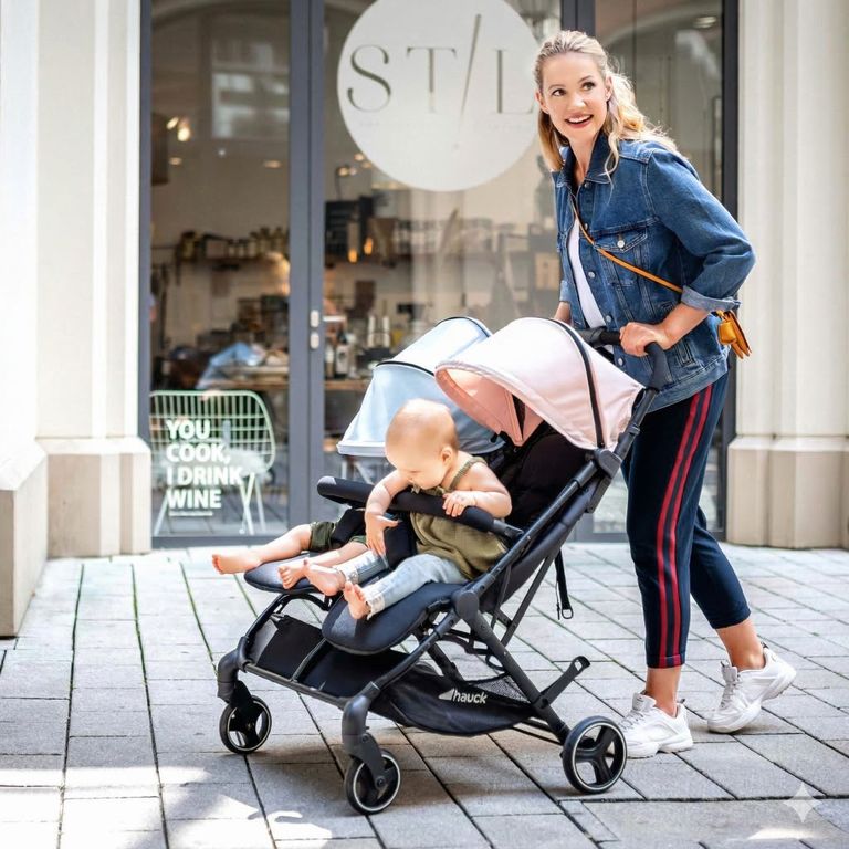 mutter schiebt zwillings-buggy mit zwillingen mädchen junge