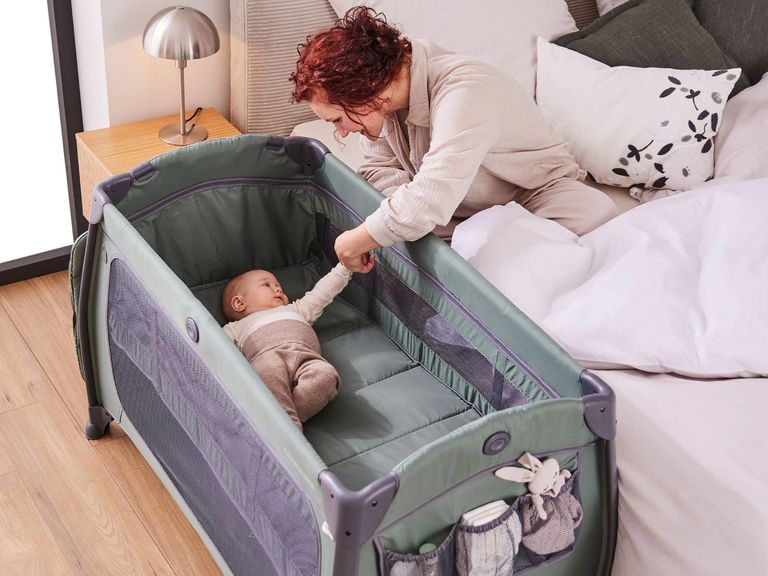 baby liegt im reisebett als beistellbett neben elternbett