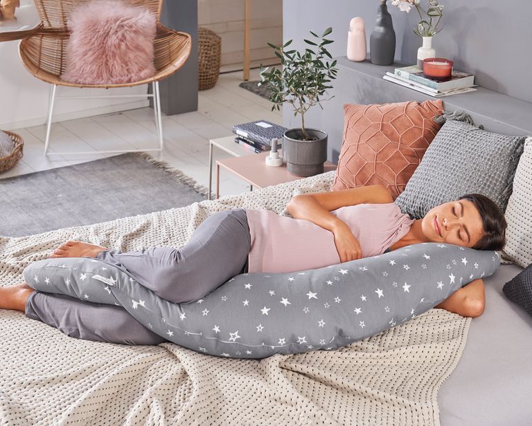 schwangere schläft auf couch mit stillkissen als stützkissen