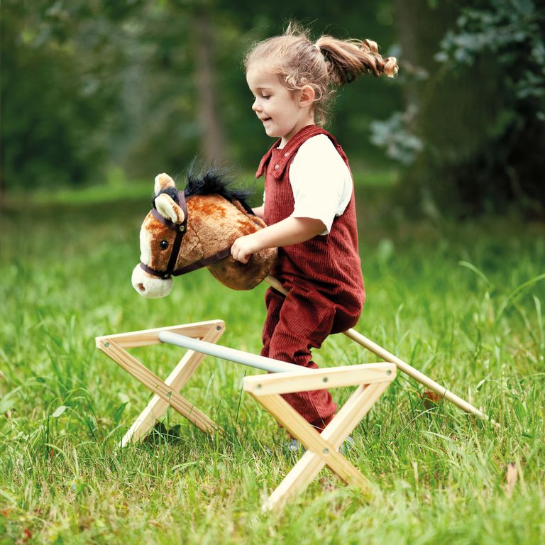 kleines mädchen spilet mit small foot steckenpferd gartenspielzeug