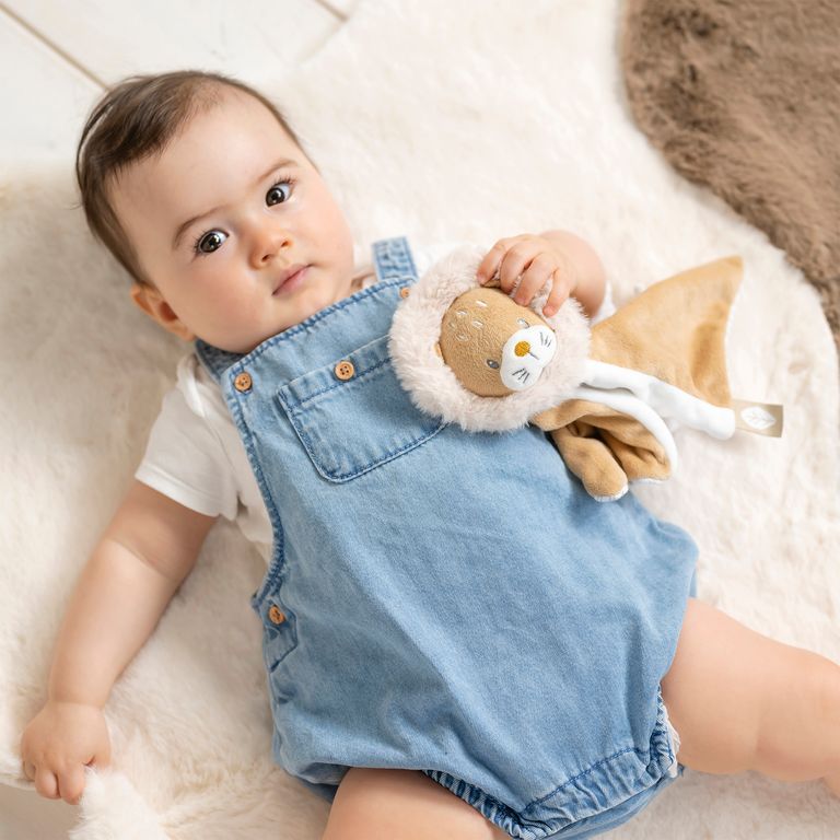 niedliches baby liegt hält schmusetuch nattou loewe ernst