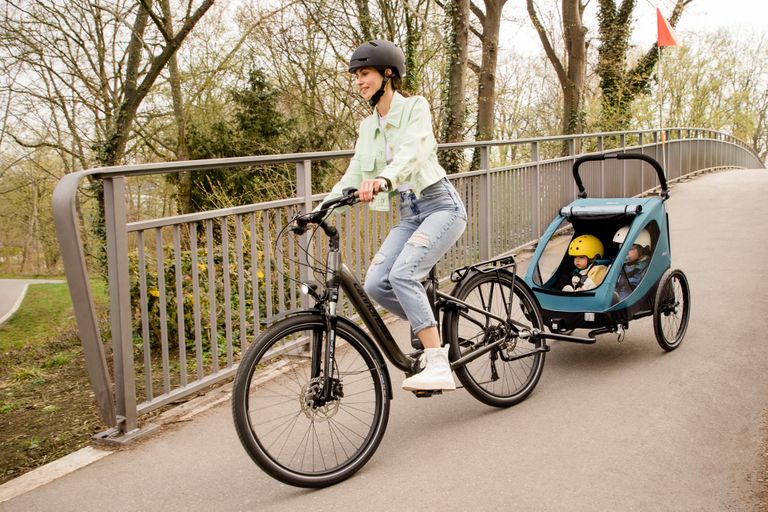 mutter fährt rad fahrradanhänger 2 kinder hauck