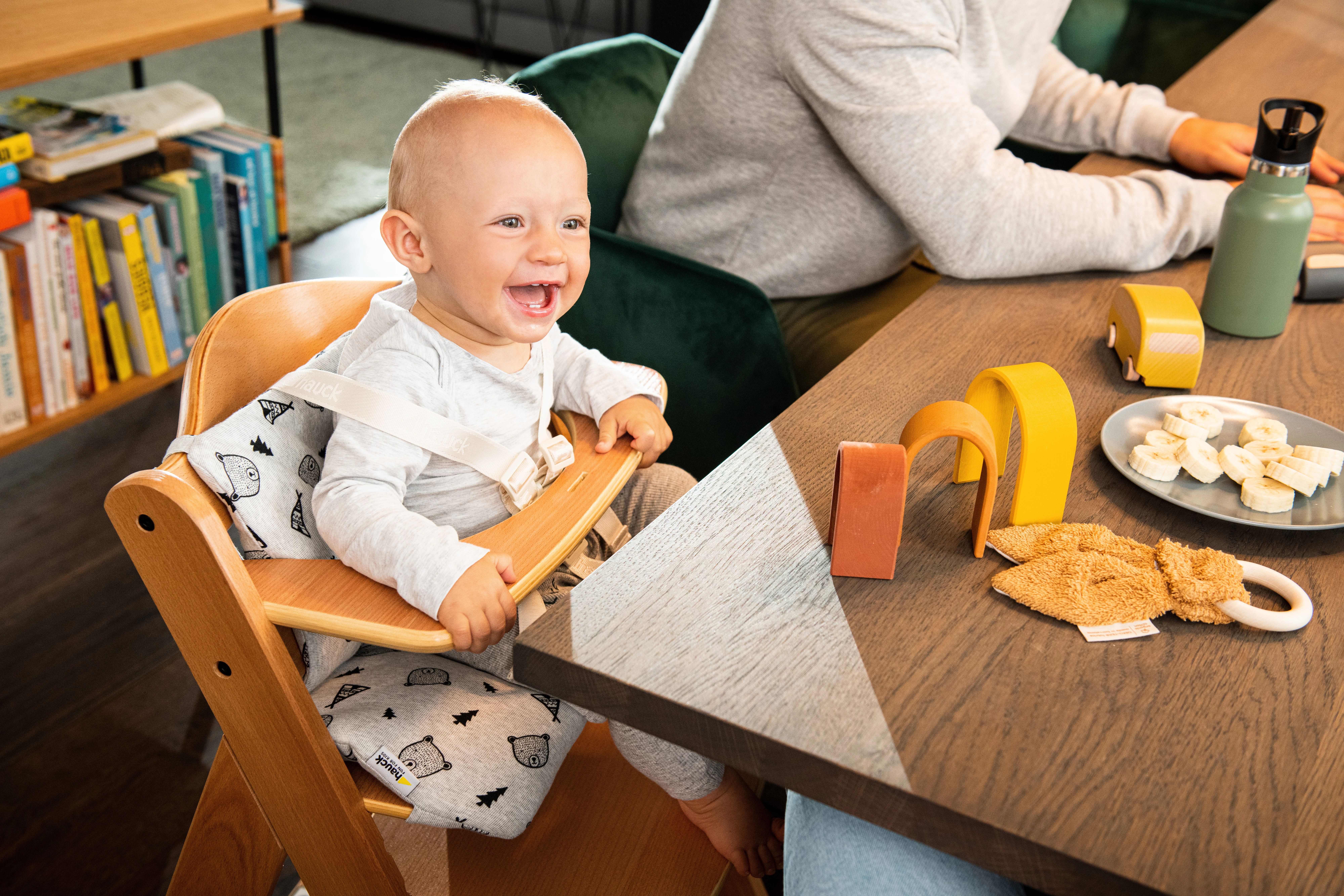 baby sitzt im mitwachsenden treppenhochstuhl am esstisch